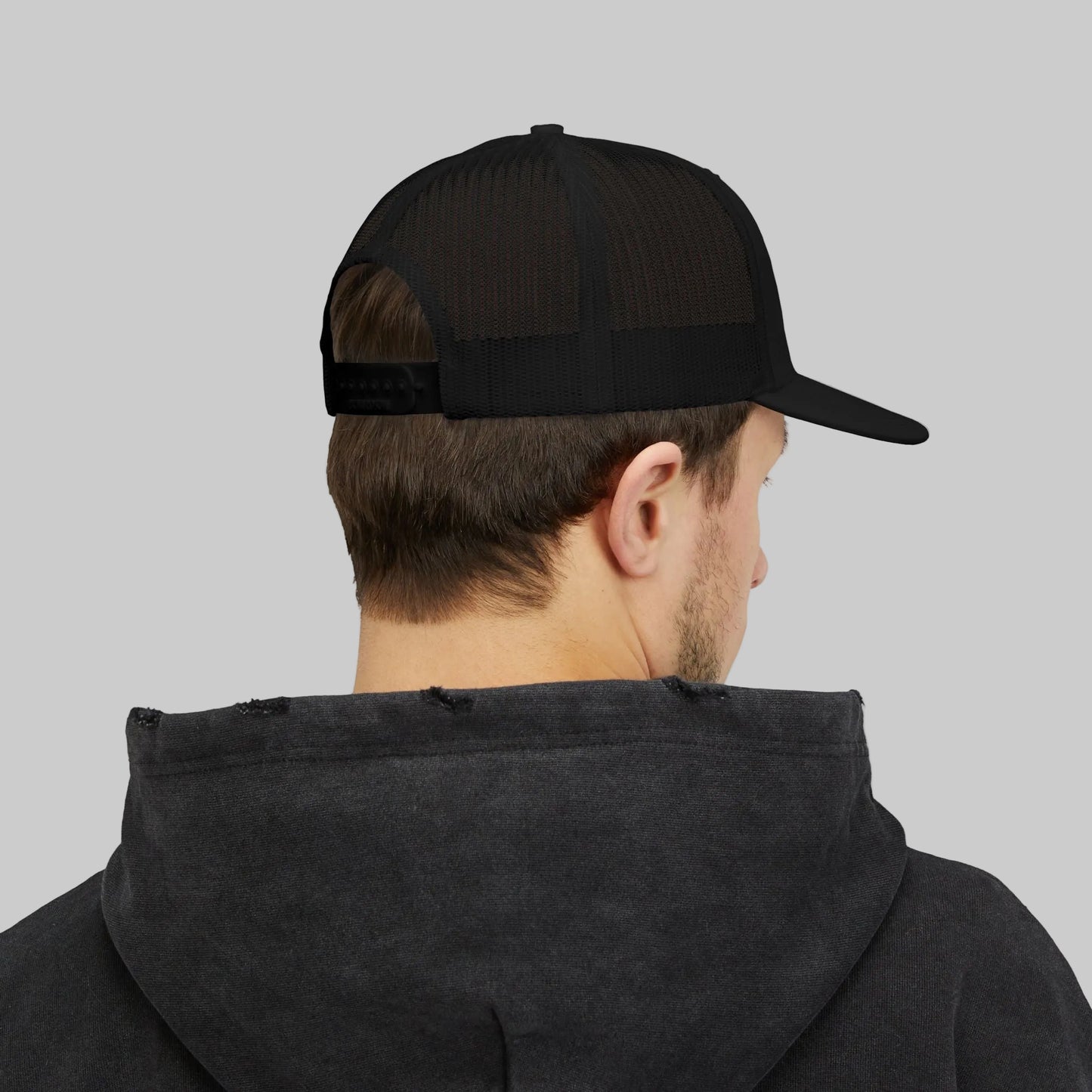 Person wearing a black cap and dark hoodie on a white background