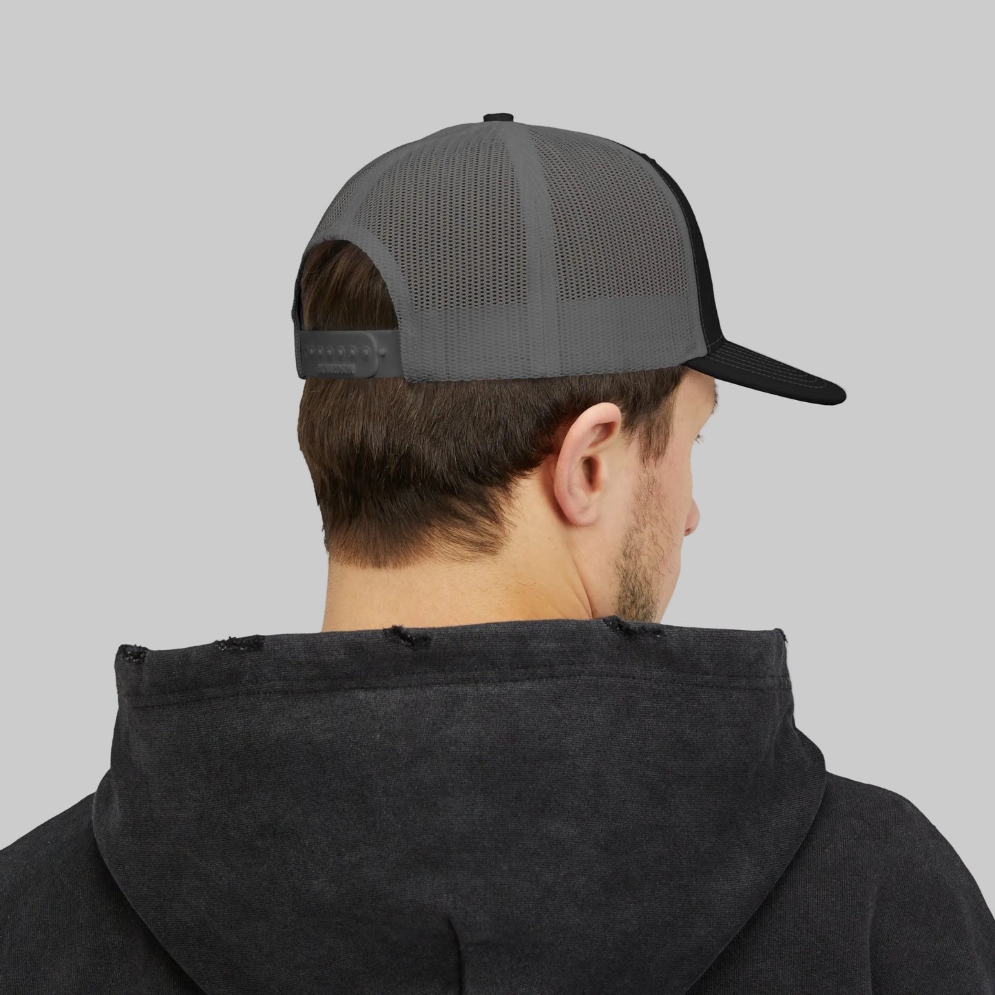 Person wearing a black hoodie and gray and black cap on a white background
