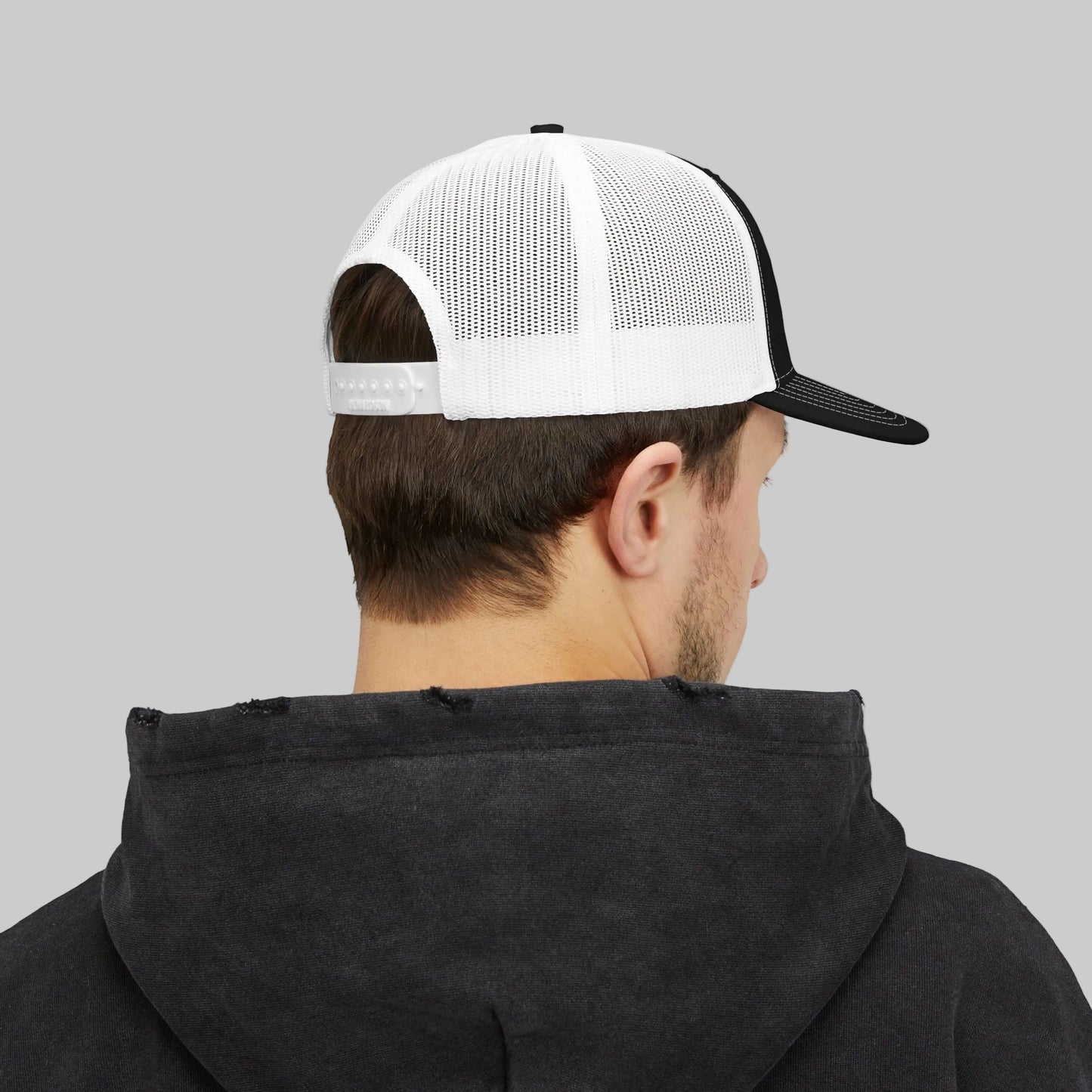 Person wearing a black hoodie and white and black cap on a white background